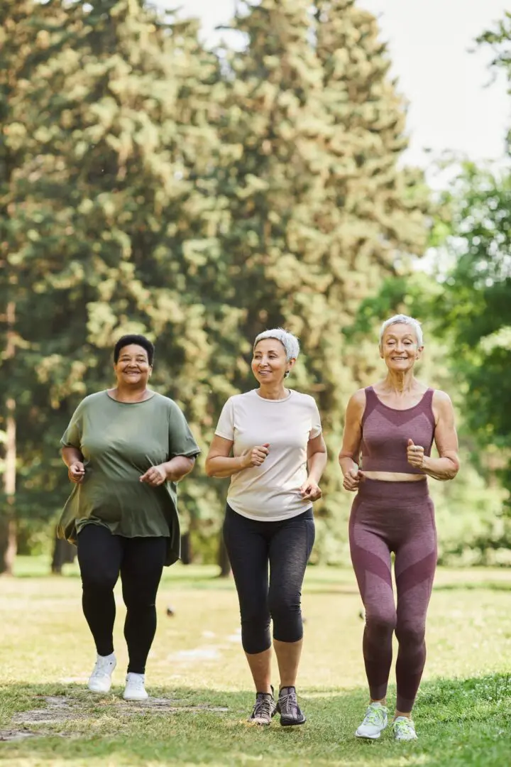 Vertical three senior women running towards camera in park and enjoying sports