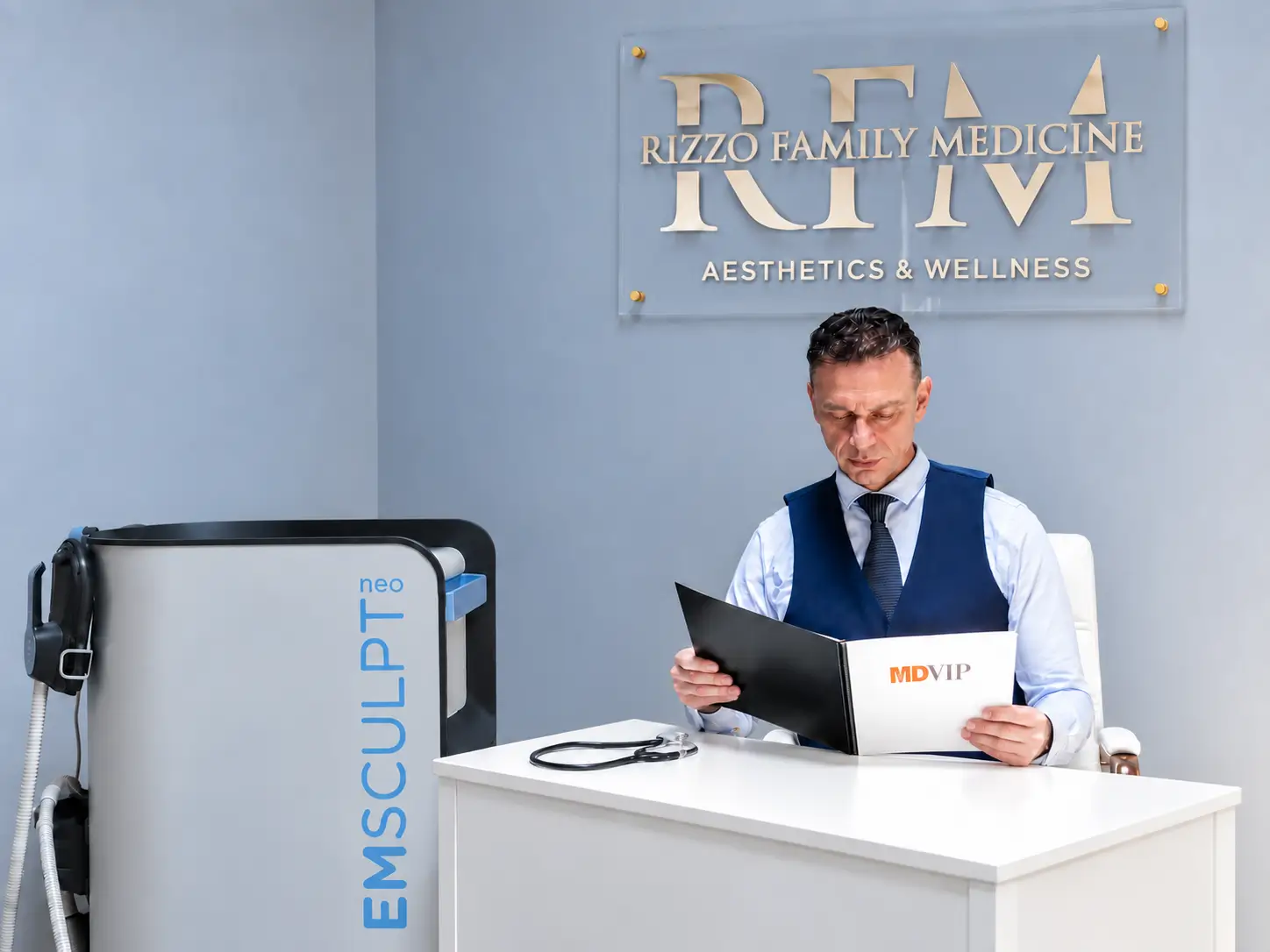 Physician reviewing brochure beside EMSCULPT machine