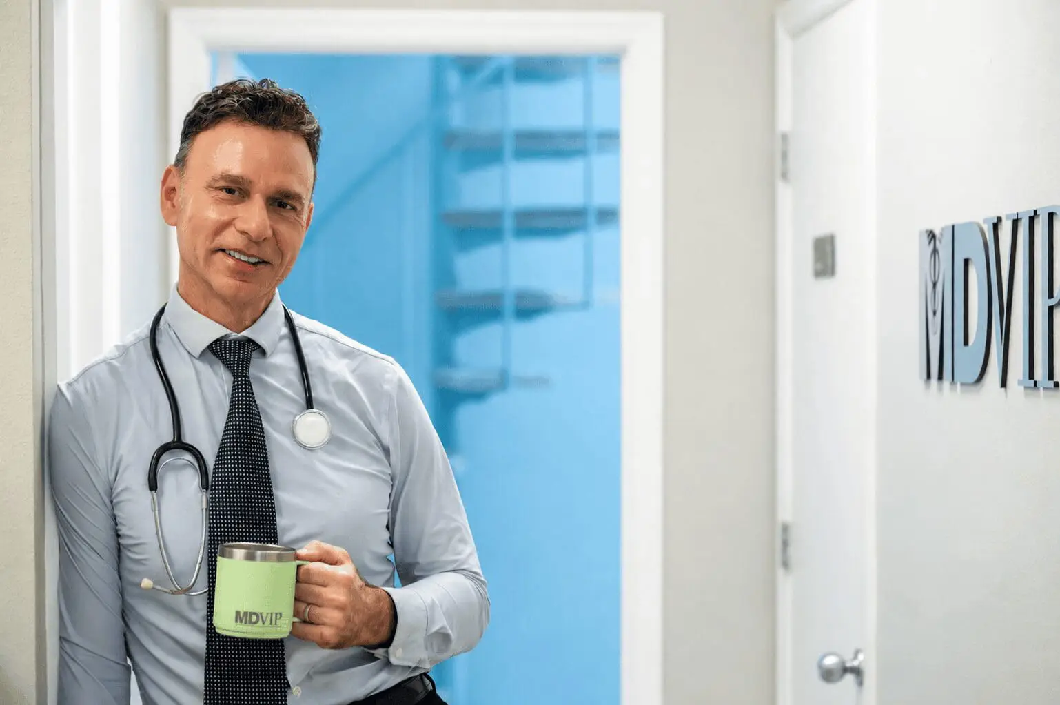 Doctor with stethoscope holding MDVIP mug